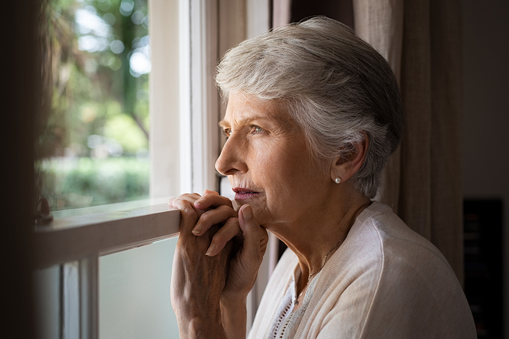 Senior woman with dementia lost looking out the window.