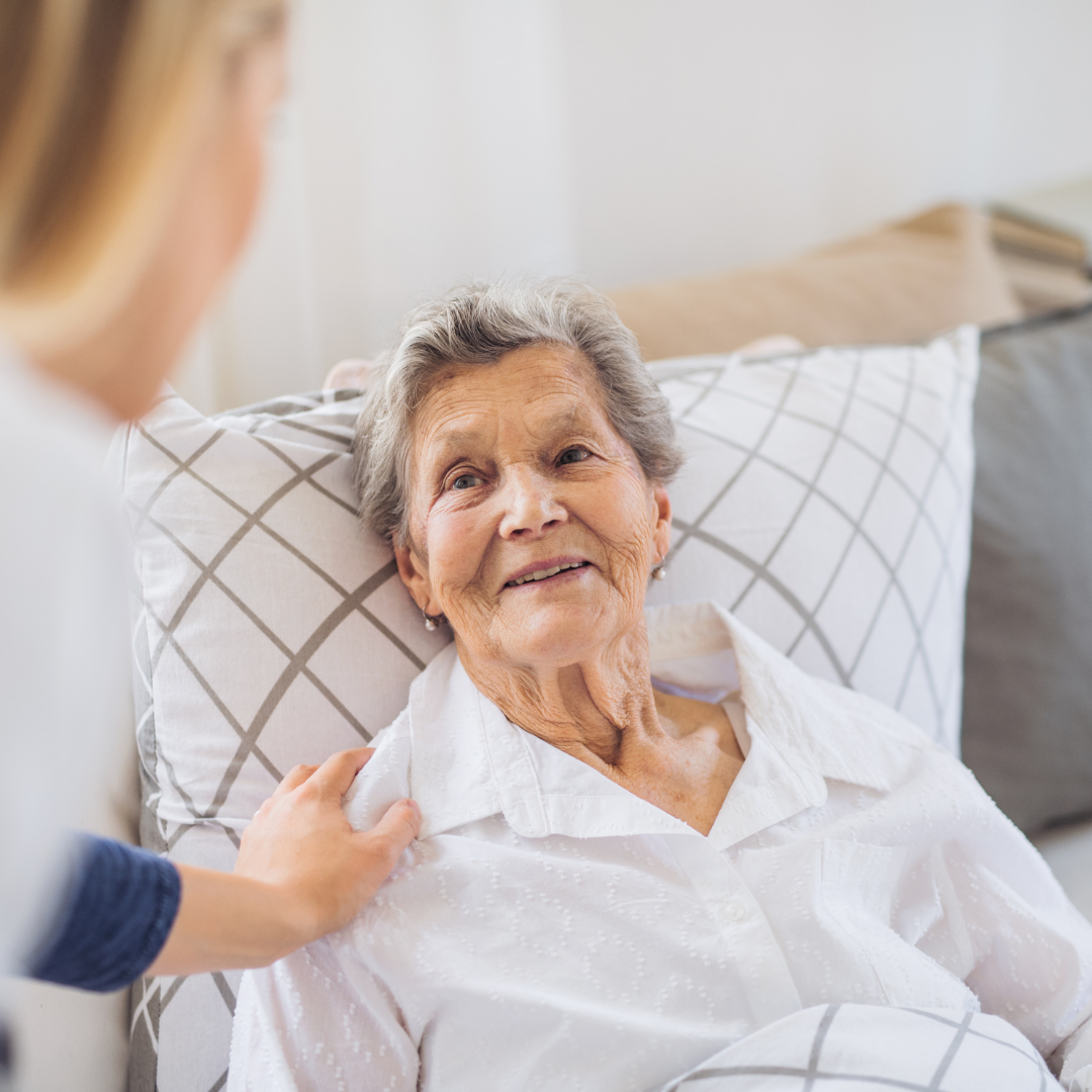 Caregiver talking to senior woman laying in bed
