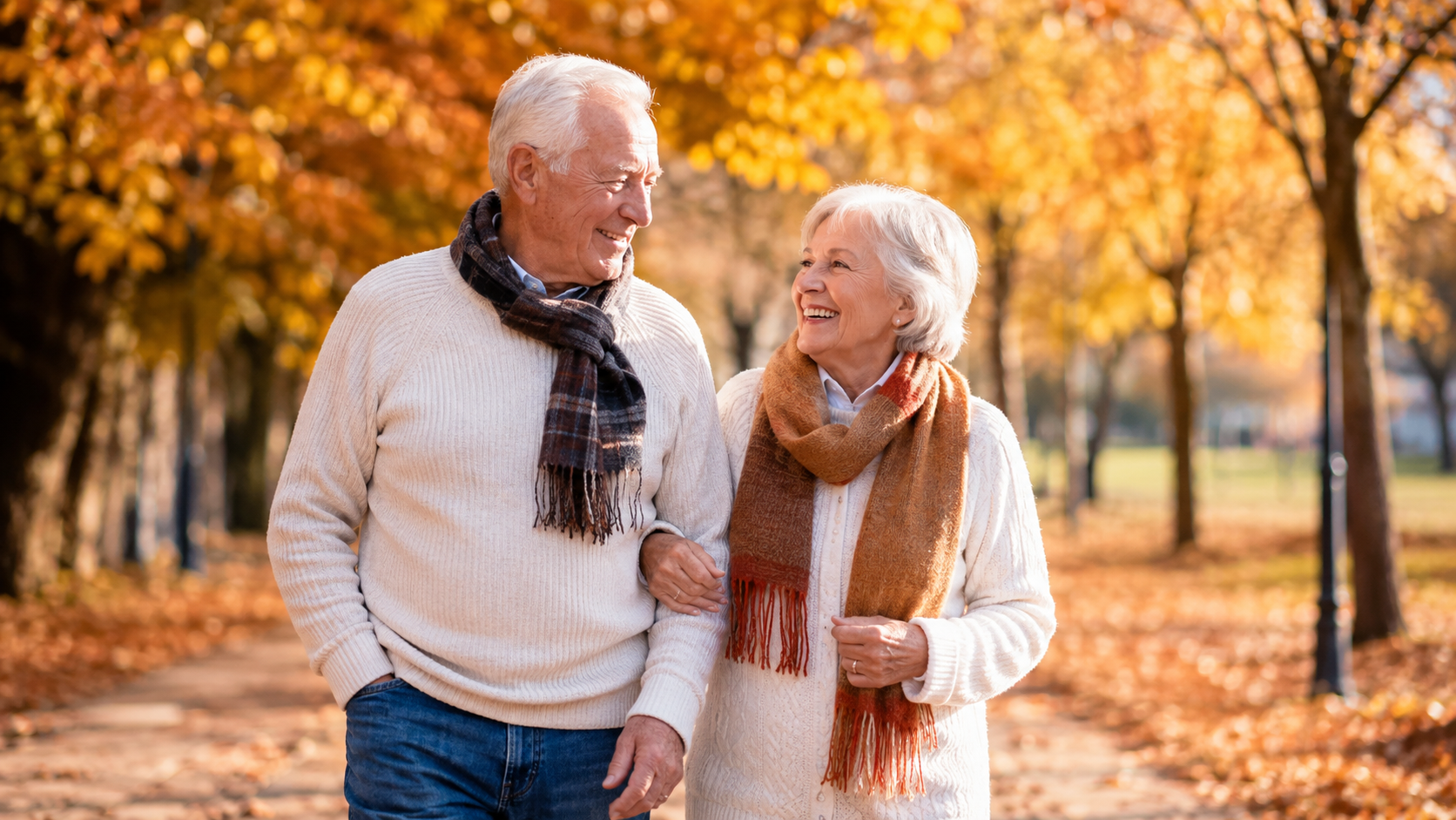 Smiling senior couple walking together along a path through golden autumn trees on a crisp fall morning
