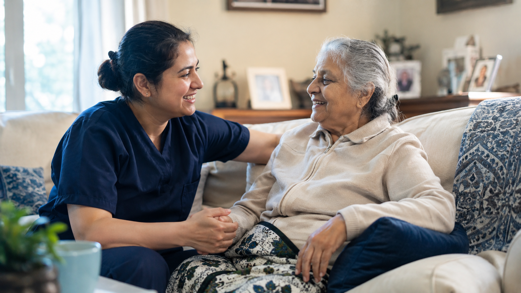 home-care-services-mississauga-caregiver-senior.jpg Home care caregiver in navy scrubs smiling and holding hands with a senior woman at home in Mississauga
